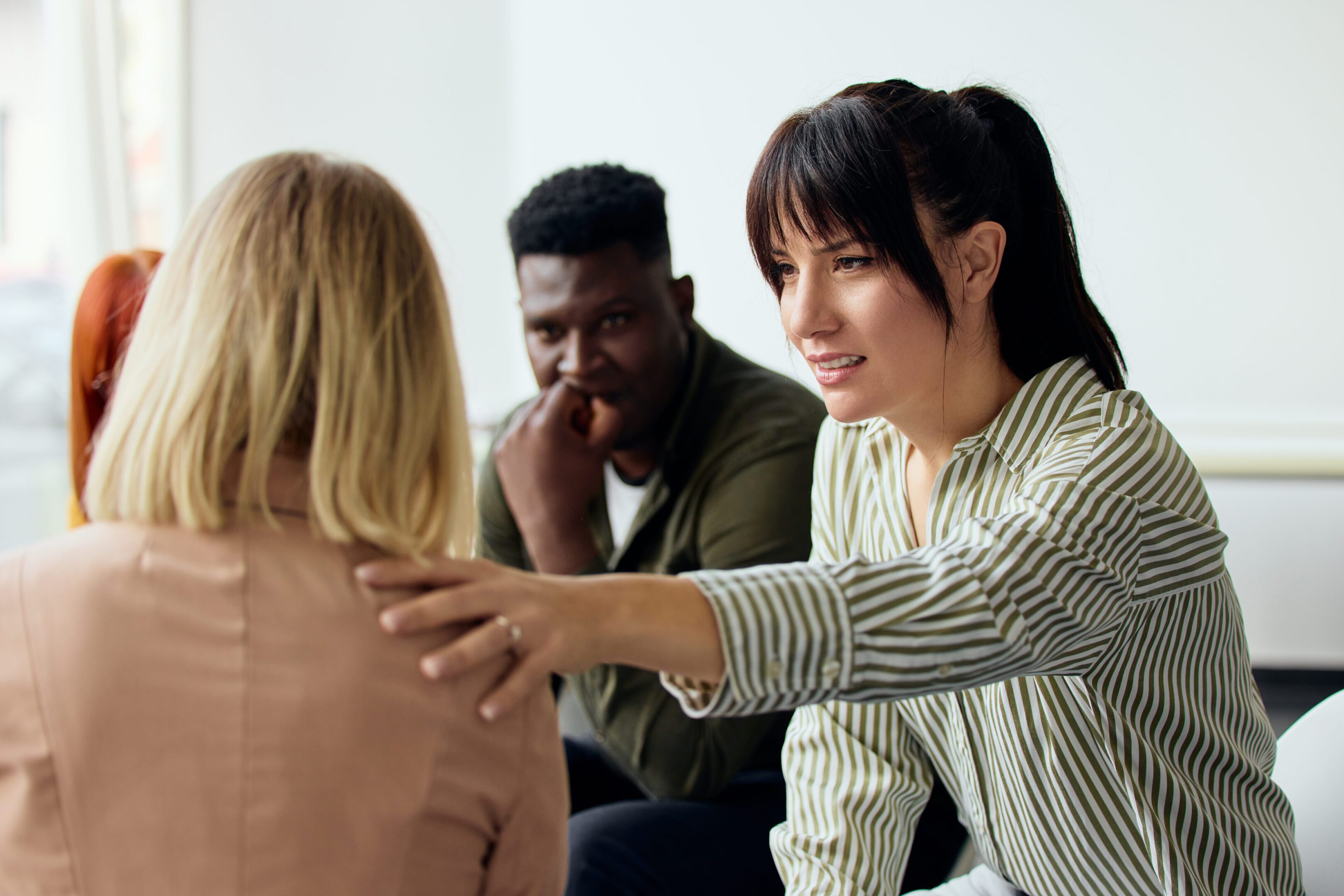 Three individuals in a supportive group setting, showcasing compassion and interpersonal communication.