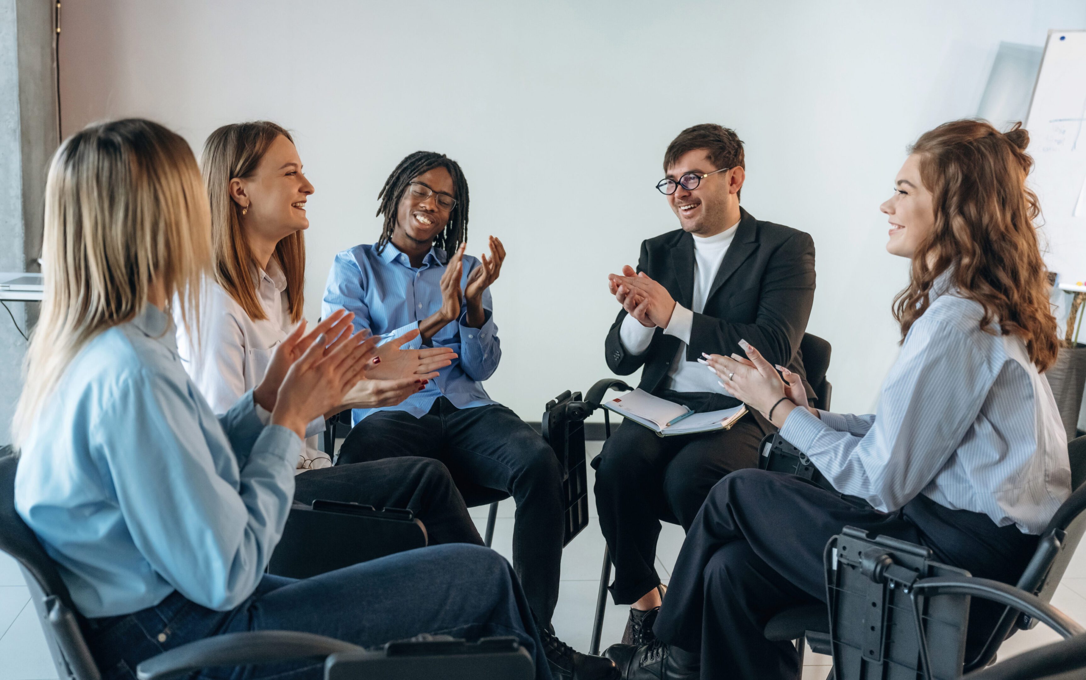 Applauding together. People are in group psychological support room.